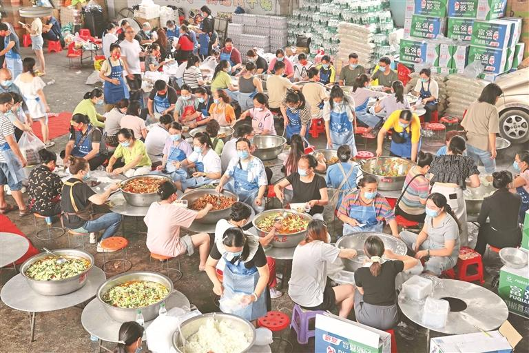 6月28日,群众在榕江县忠诚镇后勤伙食保障点帮忙打包盒饭。李长华 摄