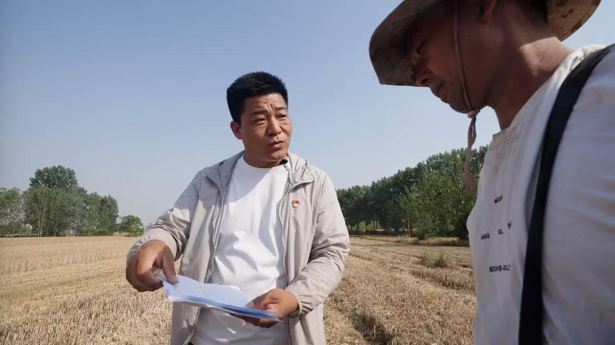 关屯乡连台村干部向跨区作业农机手杨龙银介绍麦收地图。